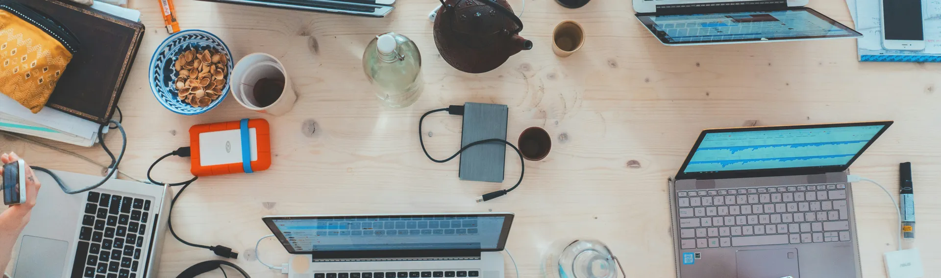 Cluttered desk with computers, smartphones, and tech accessories showcasing modern web design tools and environment.