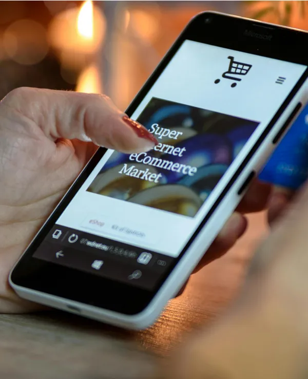 Hand taps smartphone screen showing e-commerce app with shopping cart icon and 'Super eCommerce Market' text.