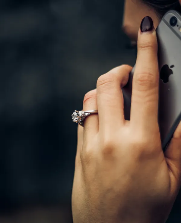 Hand holding smartphone against dark background, symbolizing 24/7 website support and hosting services.